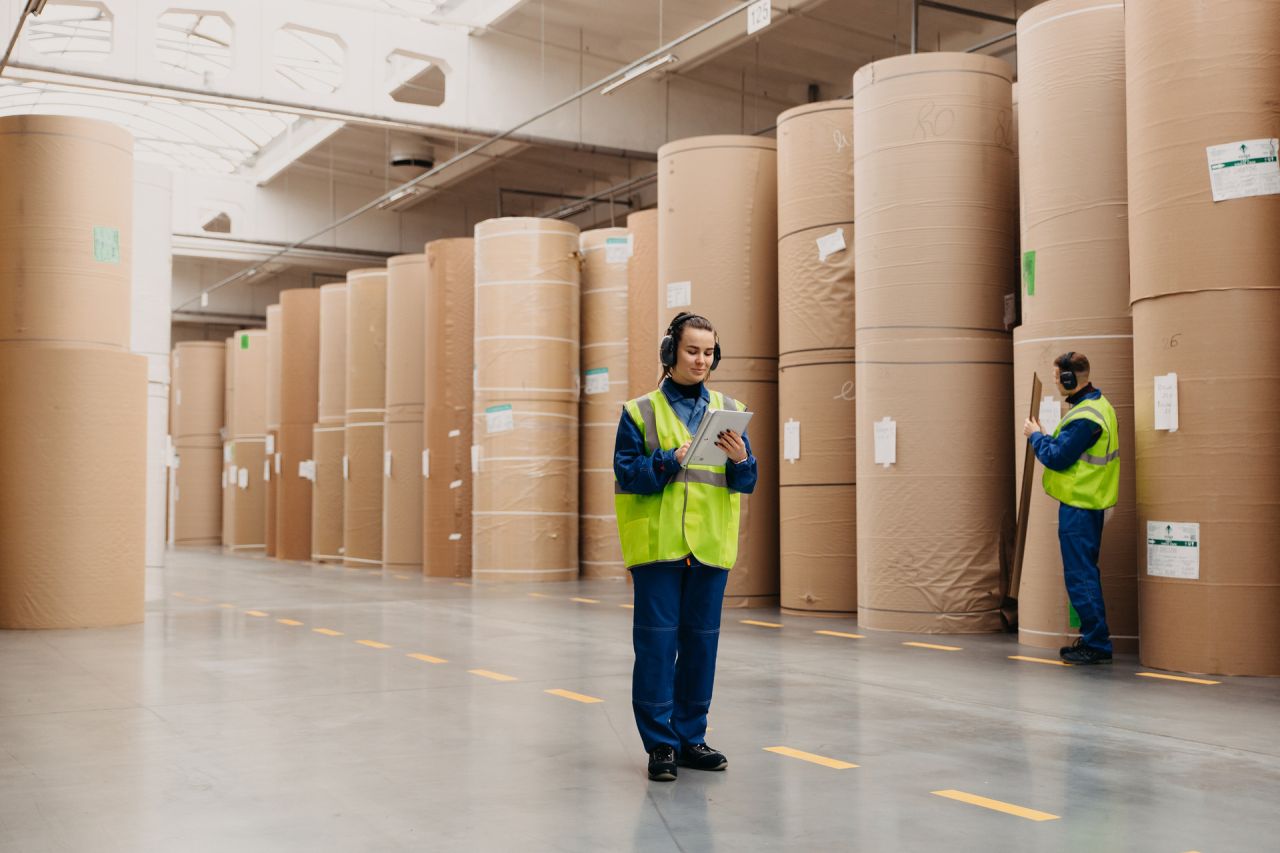 Travailleurs vérifiant des rouleaux de papier dans un entrepôt de stockage industriel.