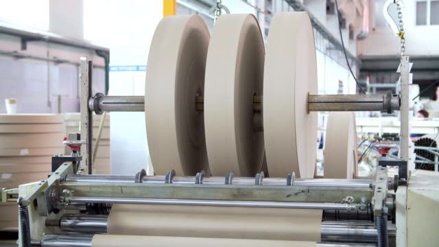 Machine industrielle découpant des rouleaux de papier pour l'emballage et la logistique.