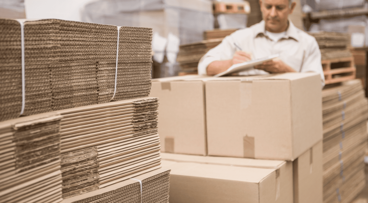 Employé vérifiant des piles de cartons ondulés pour l'emballage et la logistique industrielle